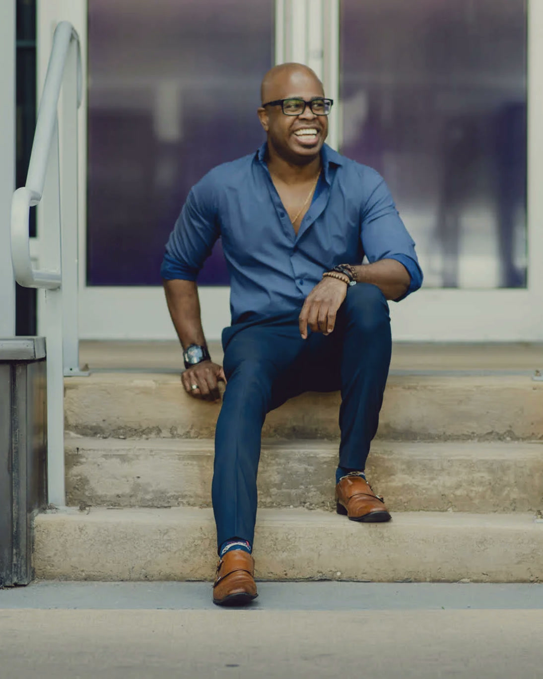 A DJ in a denim shirt seated on a set of steps
