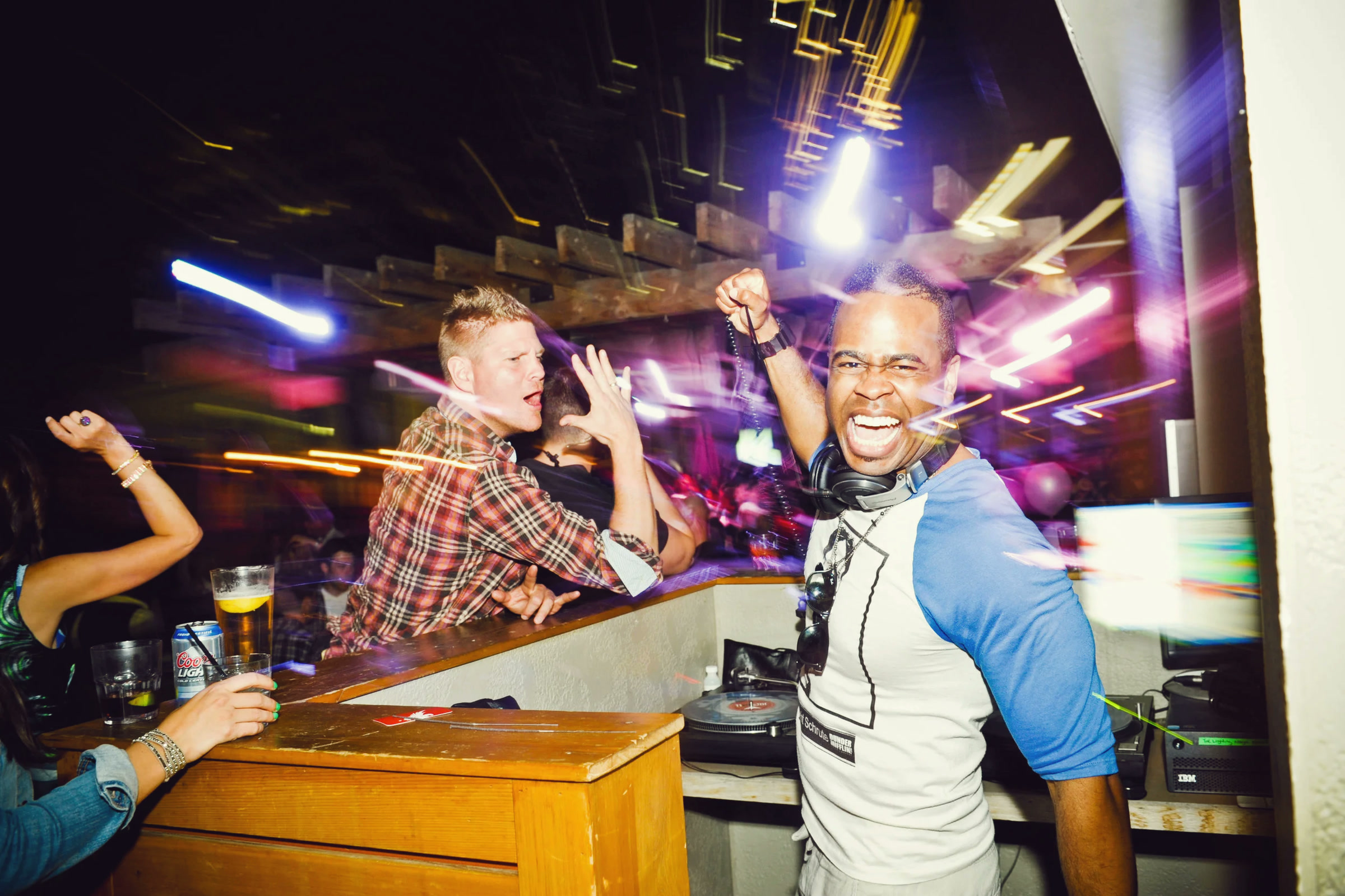A DJ cheering behind the booth as the crowd dances around him